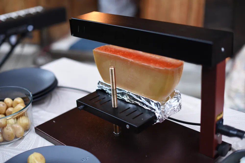 Four à raclette professionnel et demi-meule de fromage valaisan