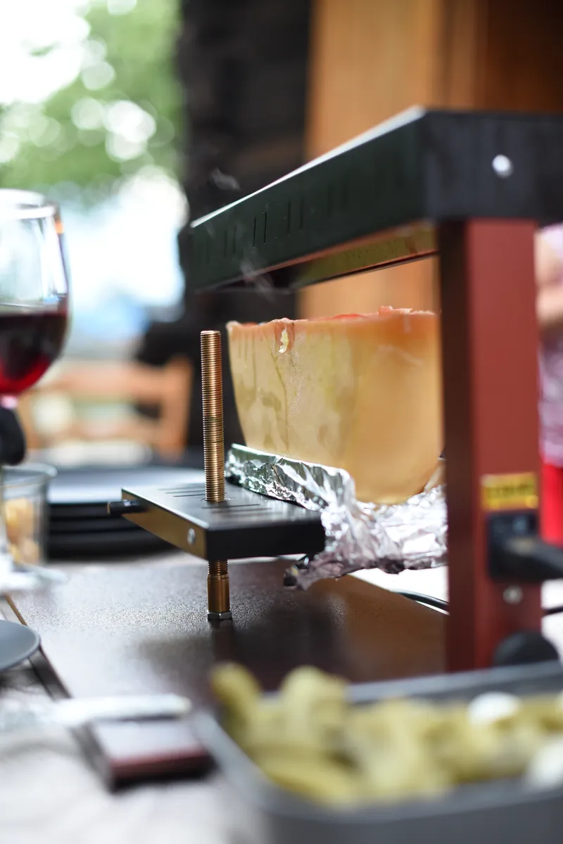 Racleuse servant la raclette valaisanne aux invités lors d'un événement